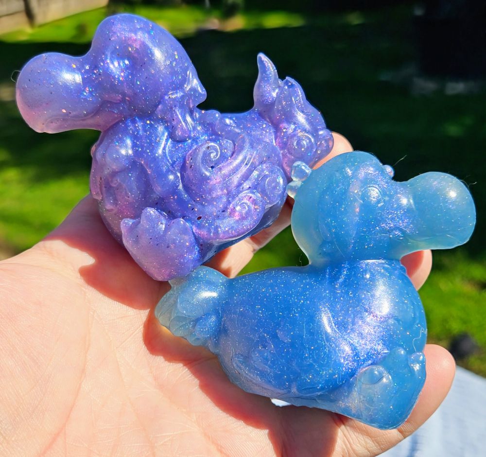 2 Dodo shaped squish, one purple one blue, held in a hand together 
