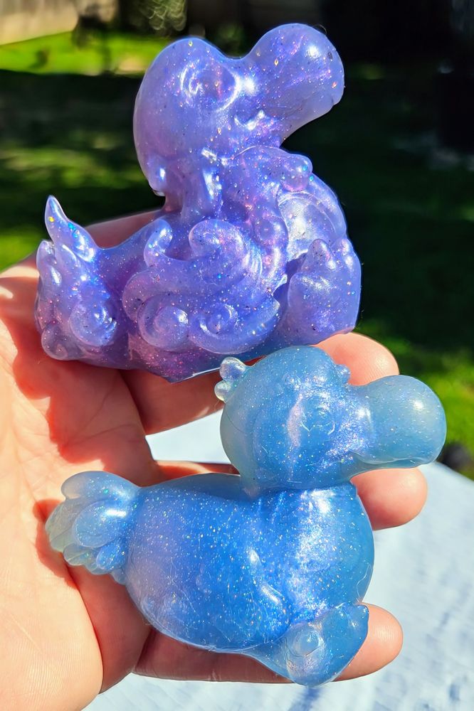 2 Dodo shaped squish, one purple one blue, held in a hand together 