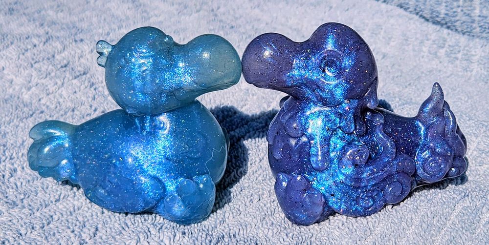 2 Dodo shaped squish, one purple one blue, put on a table facing each other 