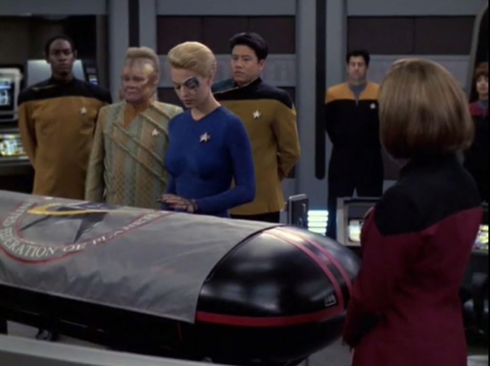 Seven of Nine speaks in honor of John Kelly, standing over a casket at a military funeral.