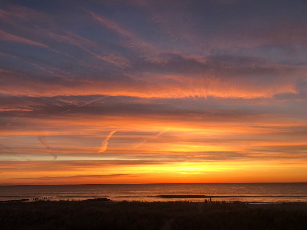 Sunrise over the Atlantic Ocean … horizontal bands of color— pearly lavender, warm-yellow, and all shades of orange— apricot, tangerine, salmon, glowing embers