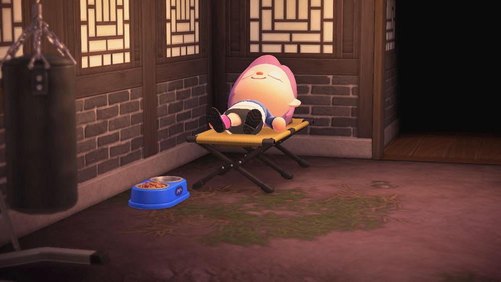 screenshot of acnh with user sleeping on a cot next to a dog bowl, with a black brick wall and dirt floor and a punching bag in the foreground 