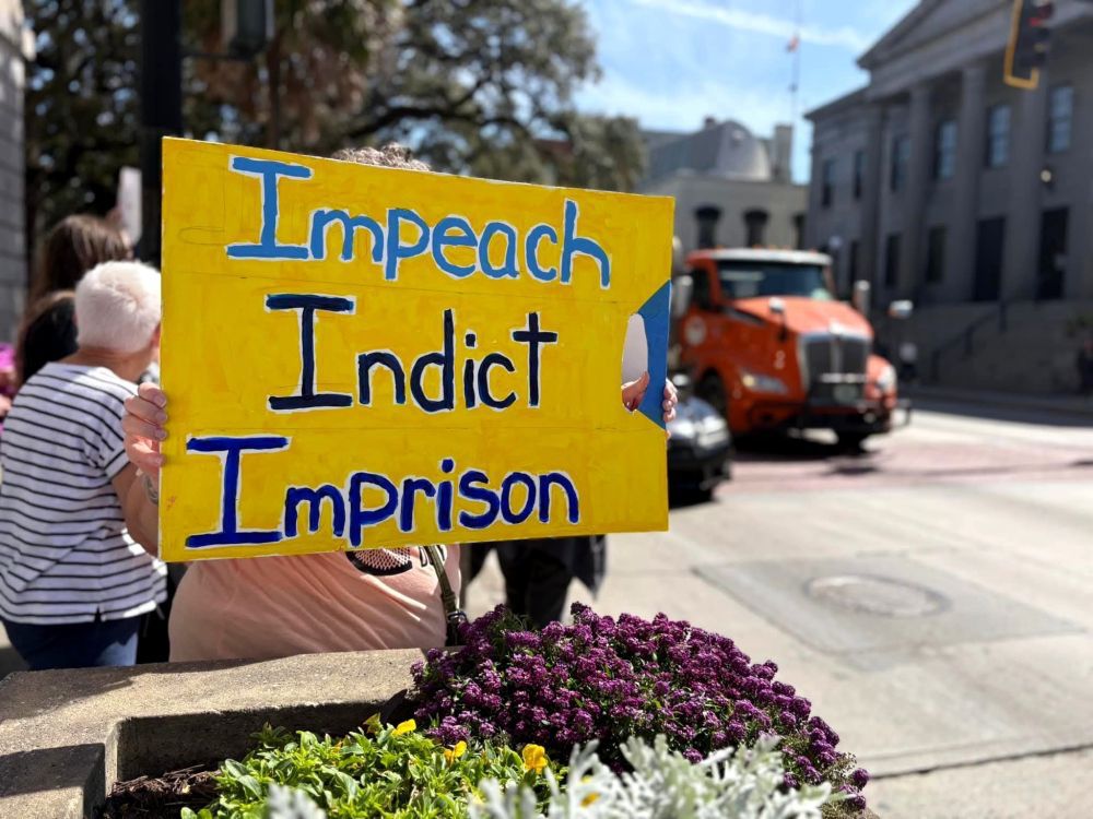A sign says “impeach, indict, imprison."