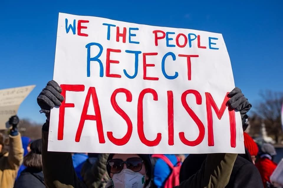 A sign says “we the people reject fascism."