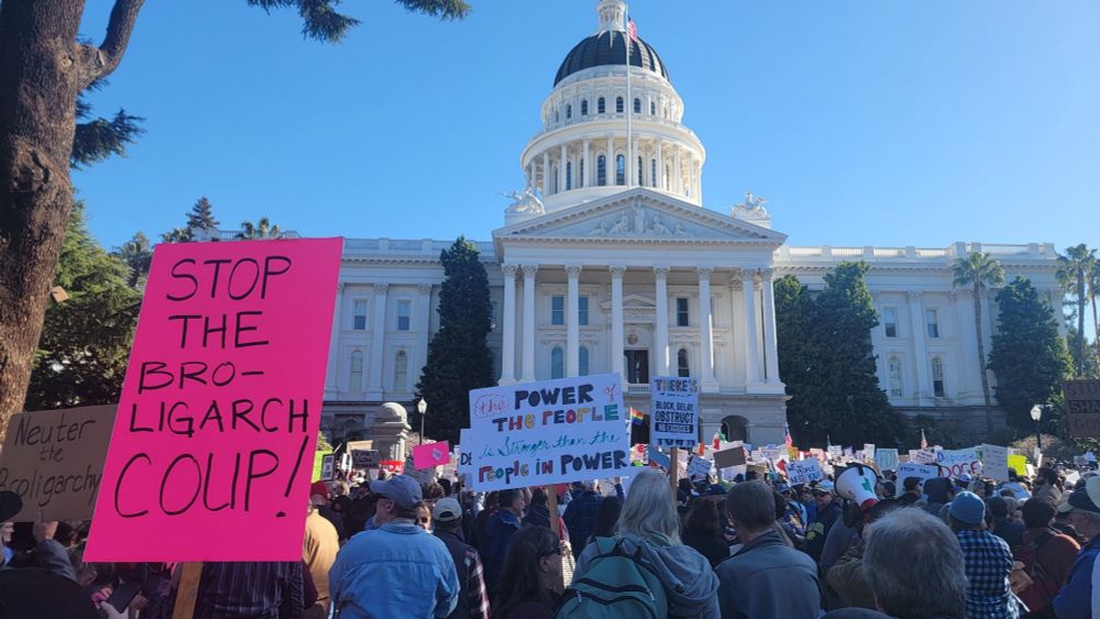 A sign says: stop the broligarchy coup.