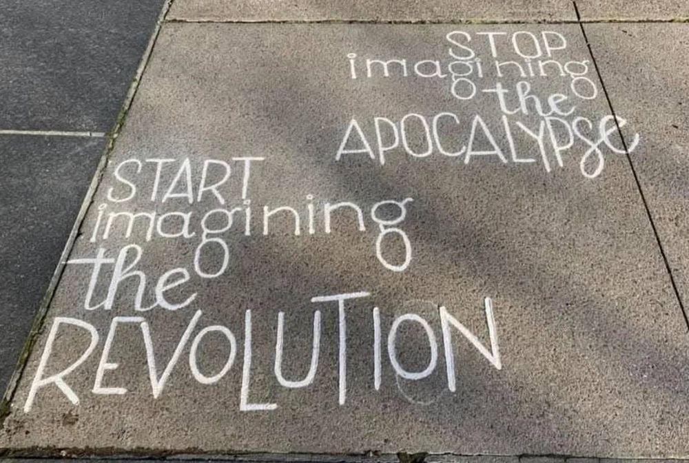 Sidewalk chalk message says: "Start imagining the revolution. Stop imagining the apocalypse."