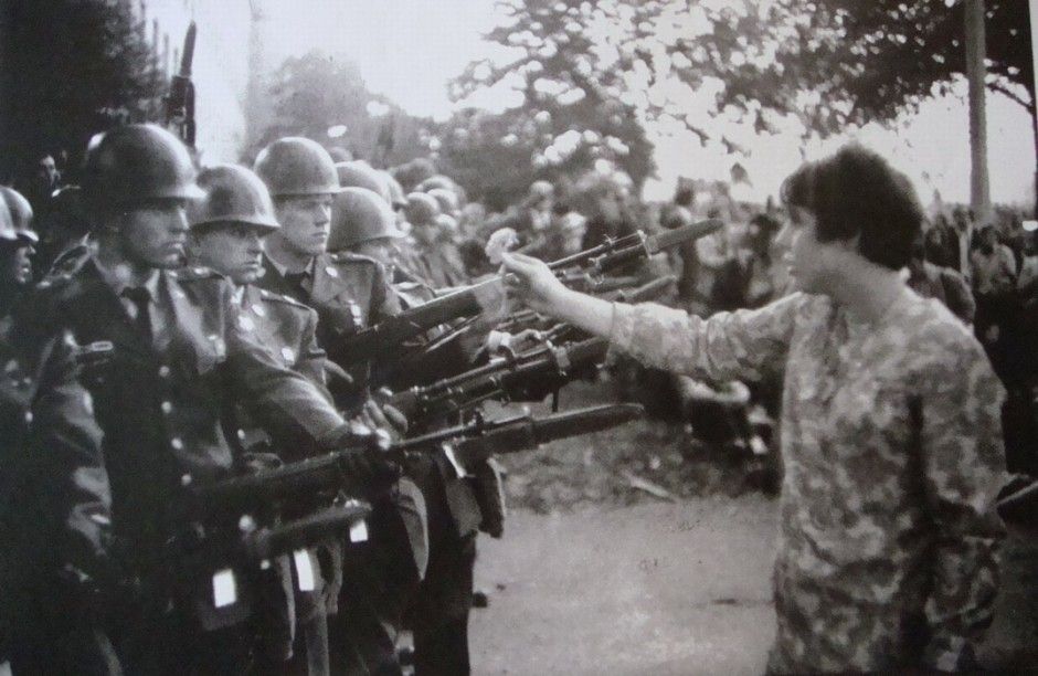 Photo of 17 year old female Vietnam Protestor holding a flower up to a line of National Guardsmen holding their rifles towards her.