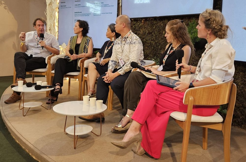 6 people seated in a row on stage at COP30. One of the people, Andy Jarvis, speaks into a mic. 