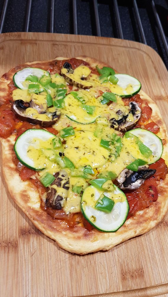 A pizza made using fat head dough (which is mostly cheese). Topped with a home made tomato sauce, sliced mushroom, chopped green bell peppers, and sliced courgette. Topped with grated cheese.