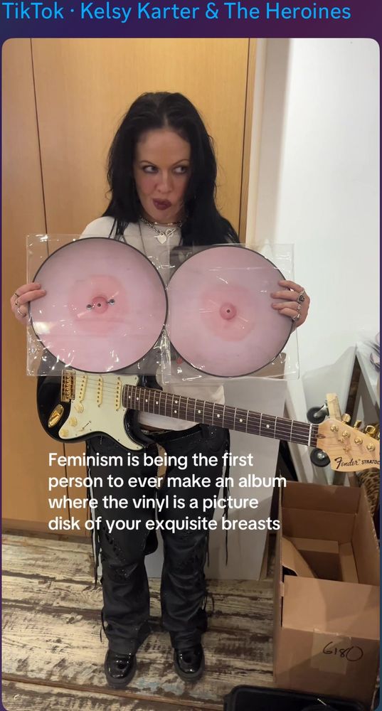 A woman holding 2 vinyls with nipples on them, and the caption saying “Feminism is being the first person to ever make an album where the vinyl is a picture disk of your exquisite breasts”