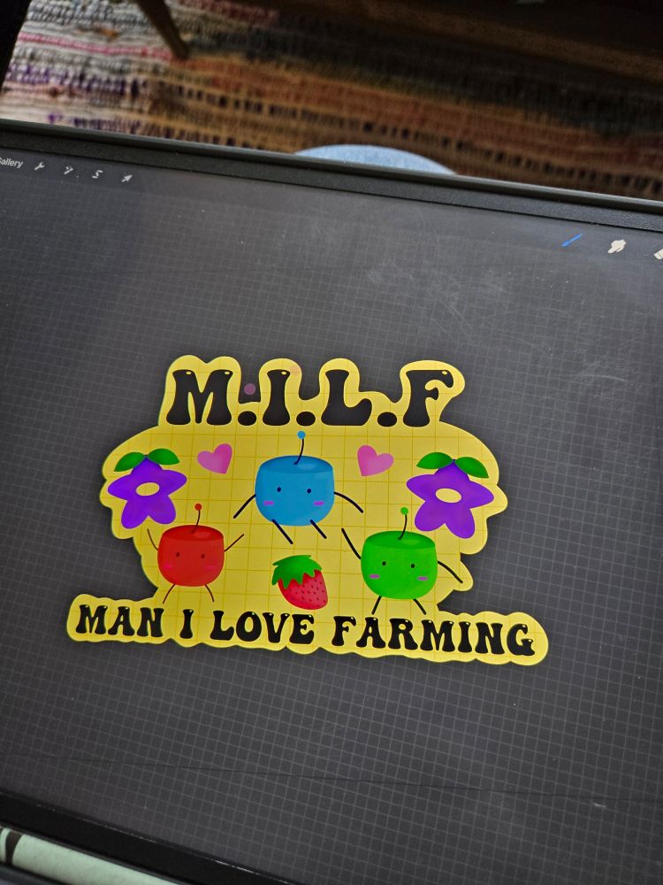 A photo of the screen of Megan's drawing tablet with a drawing app open. A sticker design with a yellow background is there with text that reads "MILF man i love farming". Around the text are cartoon drawings of stardrops, junimos, strawberries and hearts from the video game Stardew Valley