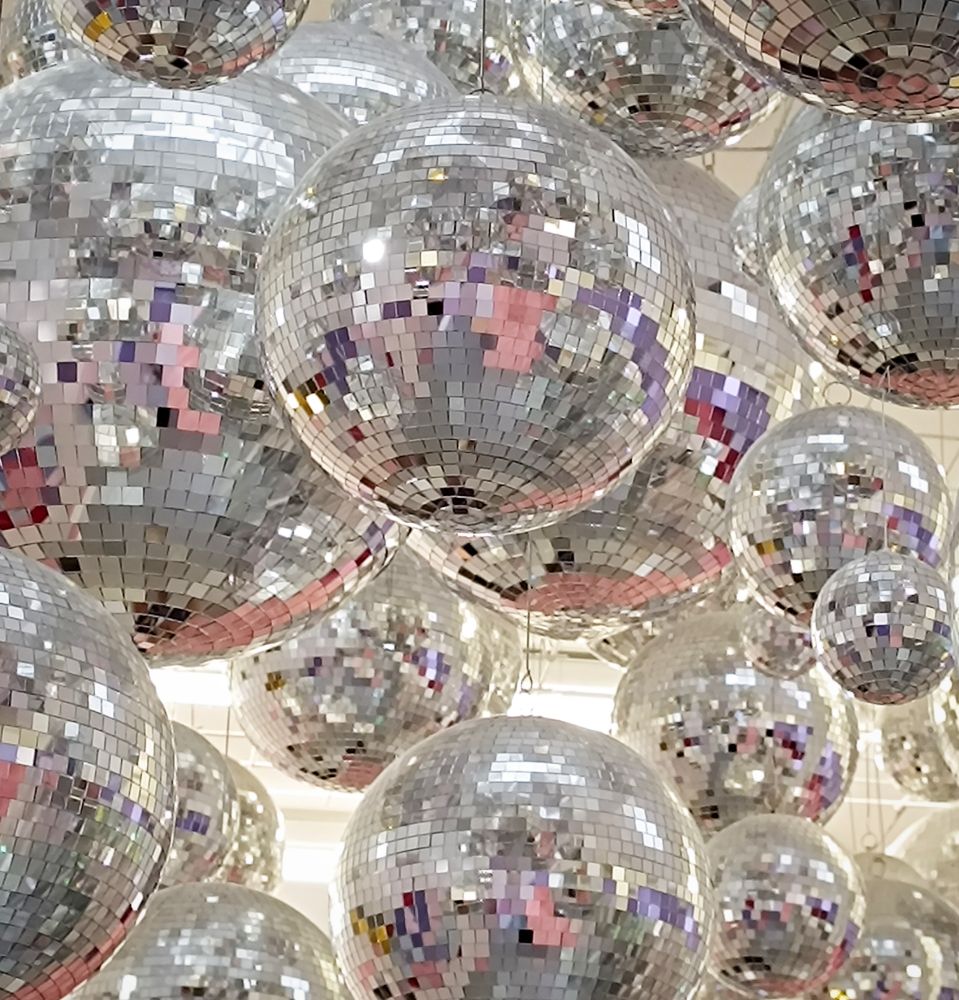 Eine große Menge an großen und kleinen Discokugeln, die von der Decke hängen.