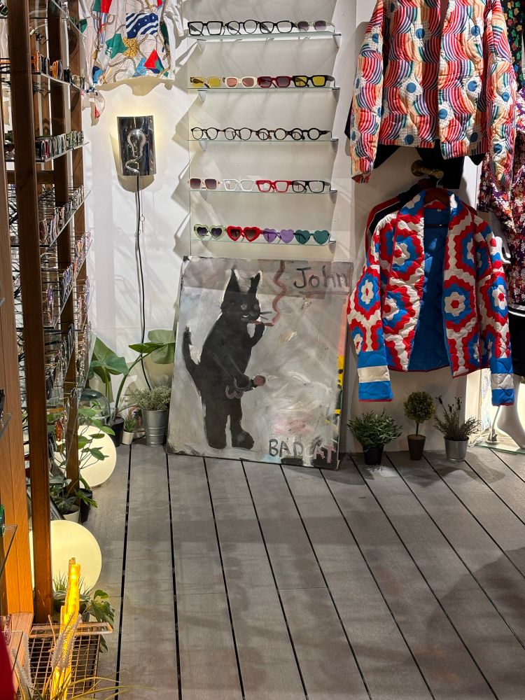 Painting showcased at the Camden Marketplace where a black cat standing on two is smoking a cigarette and stroking off their penis. Their name is John.