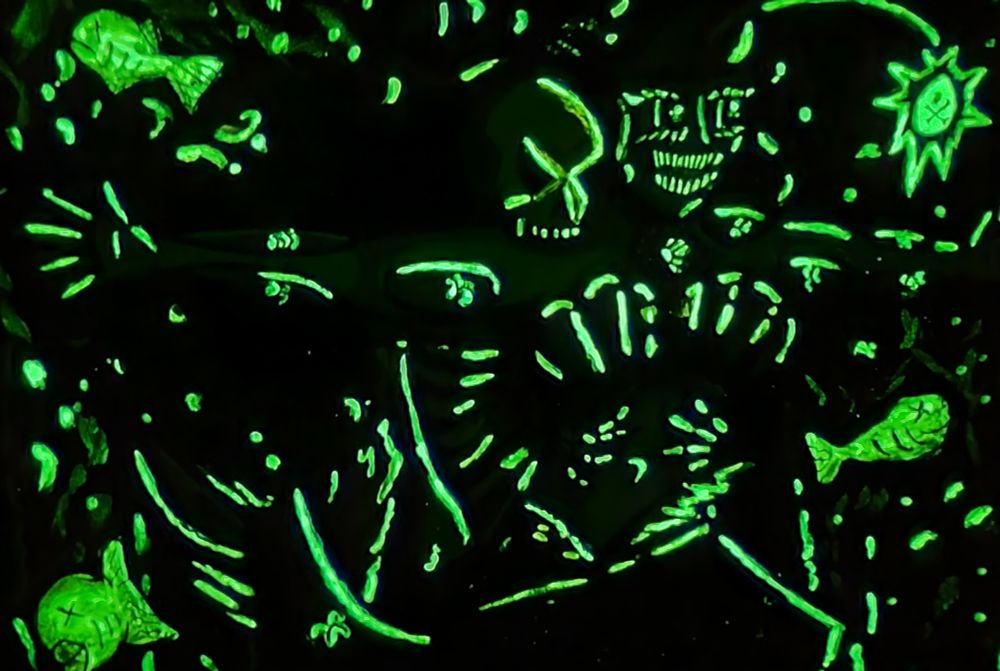 Just the glow in the dark parts of the previous image of Jack's Skeleton and deep sea mermaid pose like the Titanic. She has green skin and red hair. She has a single glow in the dark anglerfish glowing antenna in front of her, illuminating the precious jewelry from the movie.
