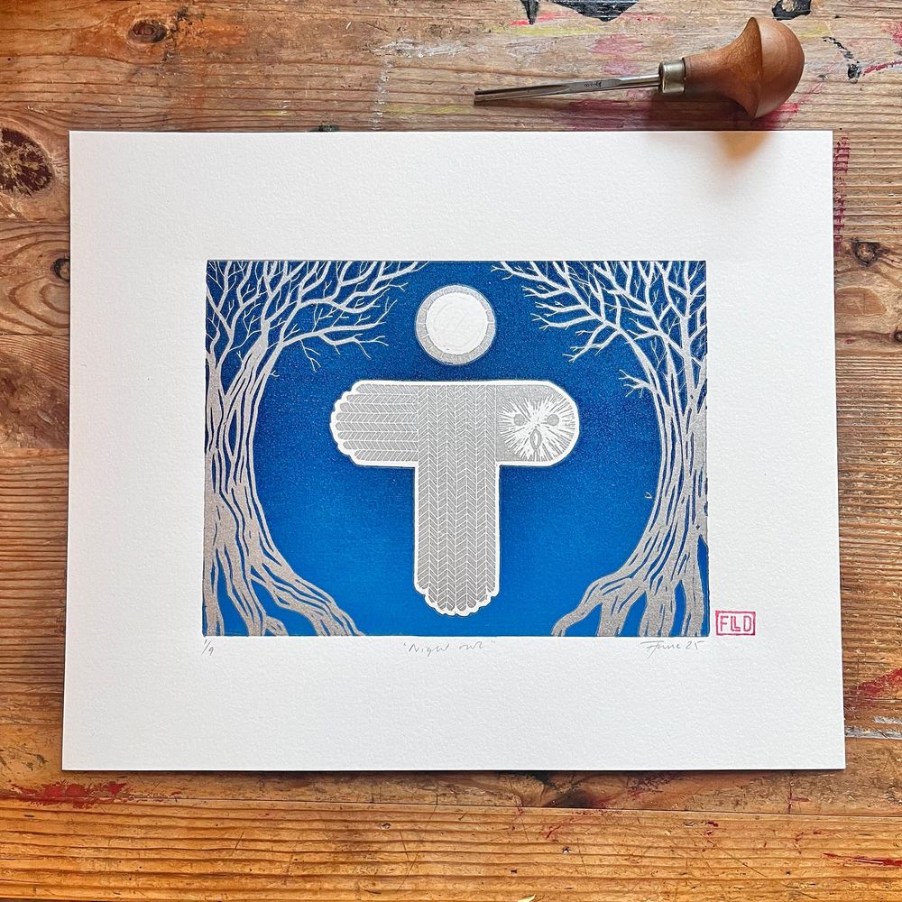 linoprint: a stylised silver owl flies under a moon between two trees