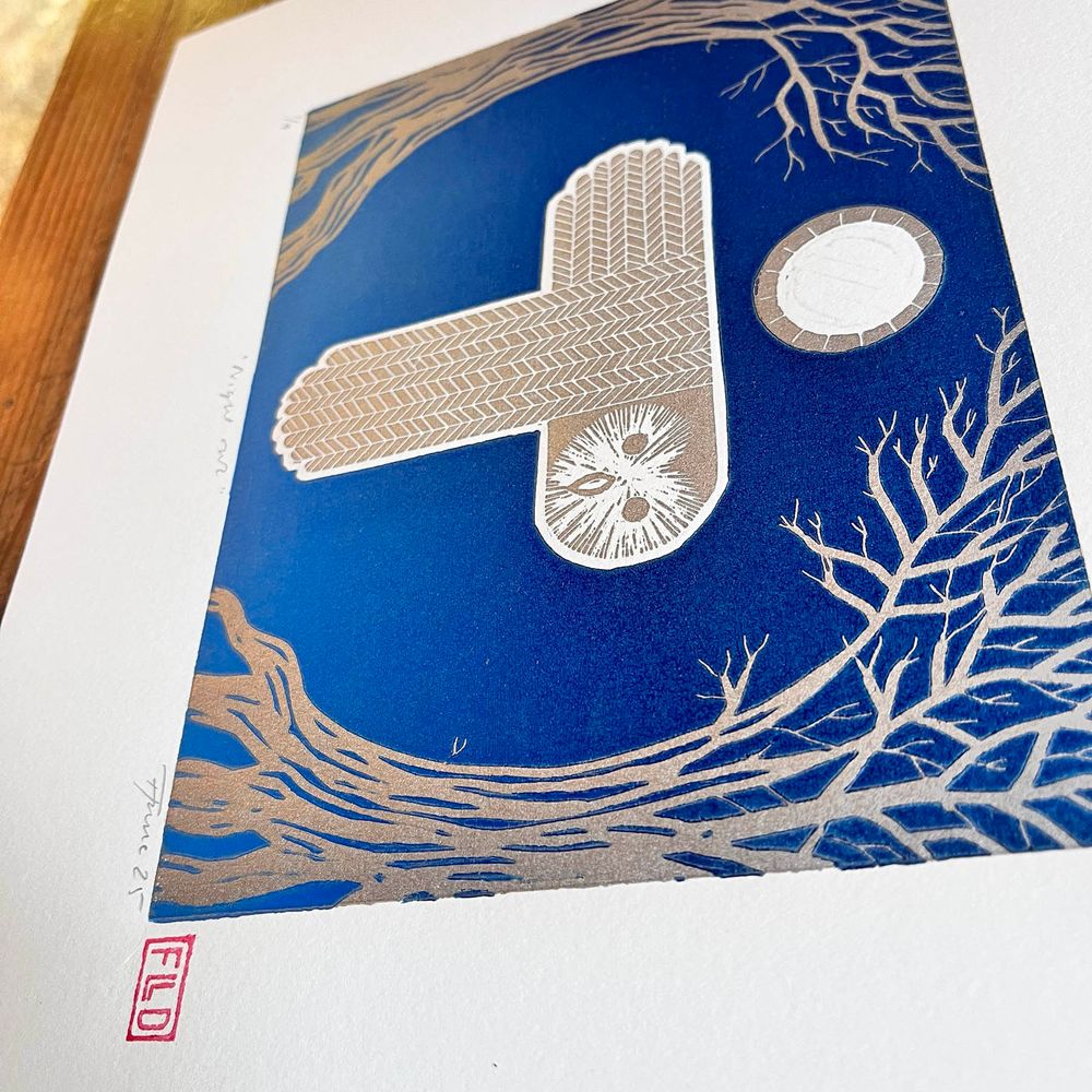 linoprint from another angle: a stylised silver owl flies under a moon between two trees