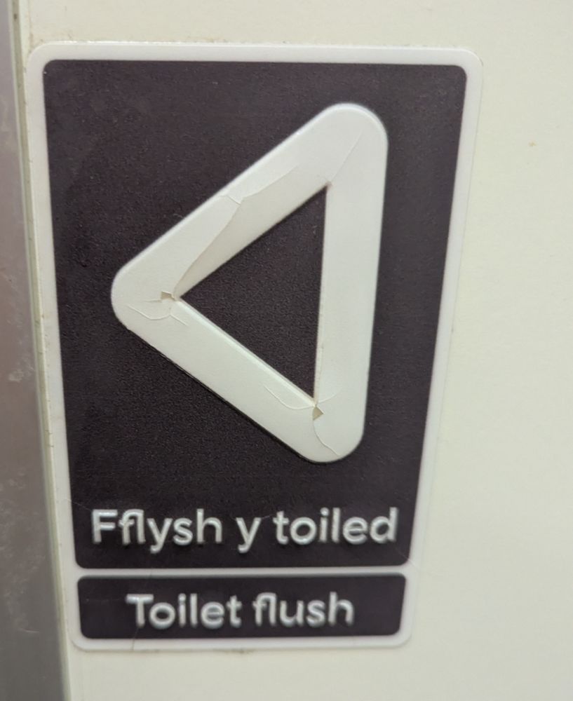 Close up of a Flush sign in a Transport for Wales train carriage in English and Welsh 