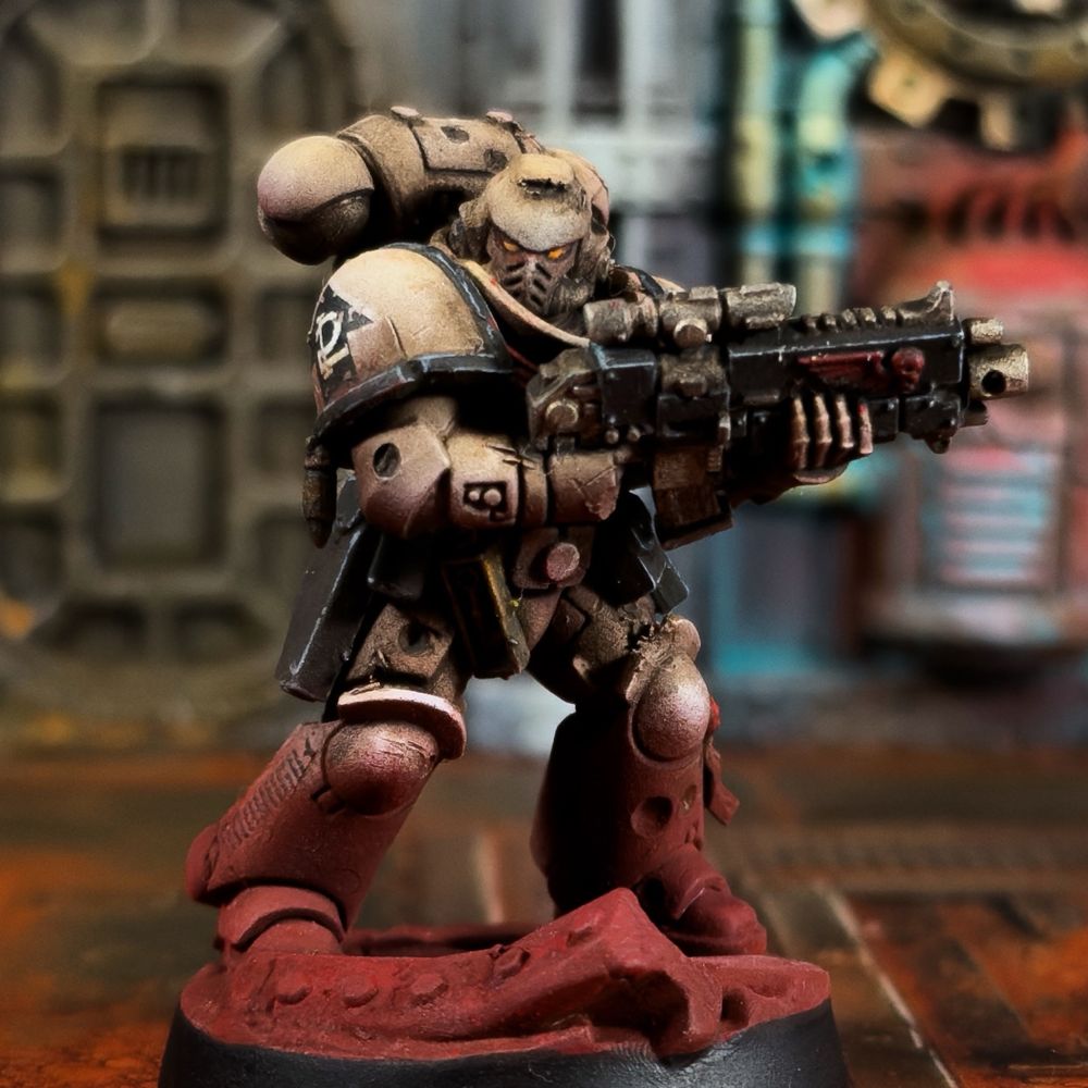 A Tome Keepers intercessor painted in the Grimdark style. He is armed with a bolt rifle. His armour is bone with black trim and weapons, with red details like the Aquila. He is looking battle-beaten and grimy, like he’s been in the field for a very long time. His base and lower legs are caked in red dust. 