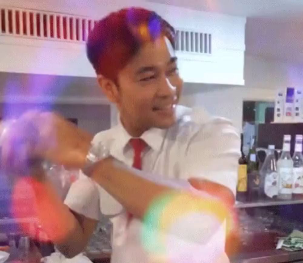 a man in a white shirt and red tie is smiling and dancing in a kitchen .