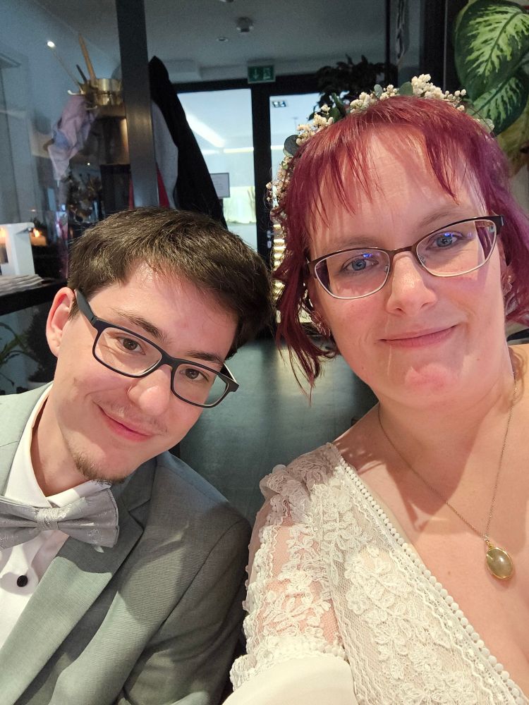 Selfie von Nate links im Anzug und mir im Brautkleid.
Wir sind beide ungefähr bis zur Brust zu sehen und sitzen