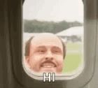 a bald man with a mustache is looking out of an airplane window .