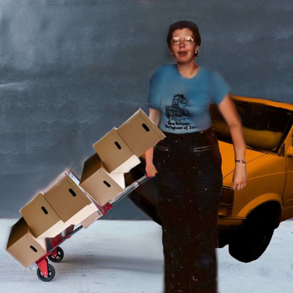 Sweating woman holds a hand truck up stacked with 6 file boxes. Behind her is an orange van.