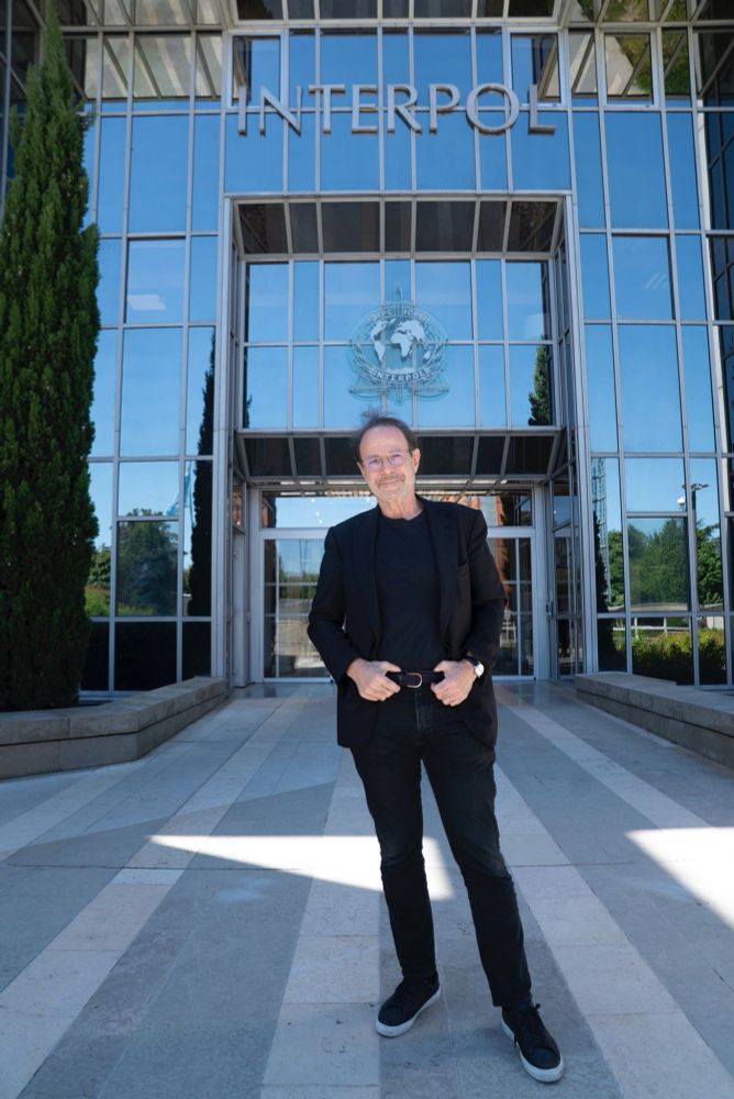 French novelist Marc Levy dressed in black standing outside INTERPOL headquarters in Lyon, France