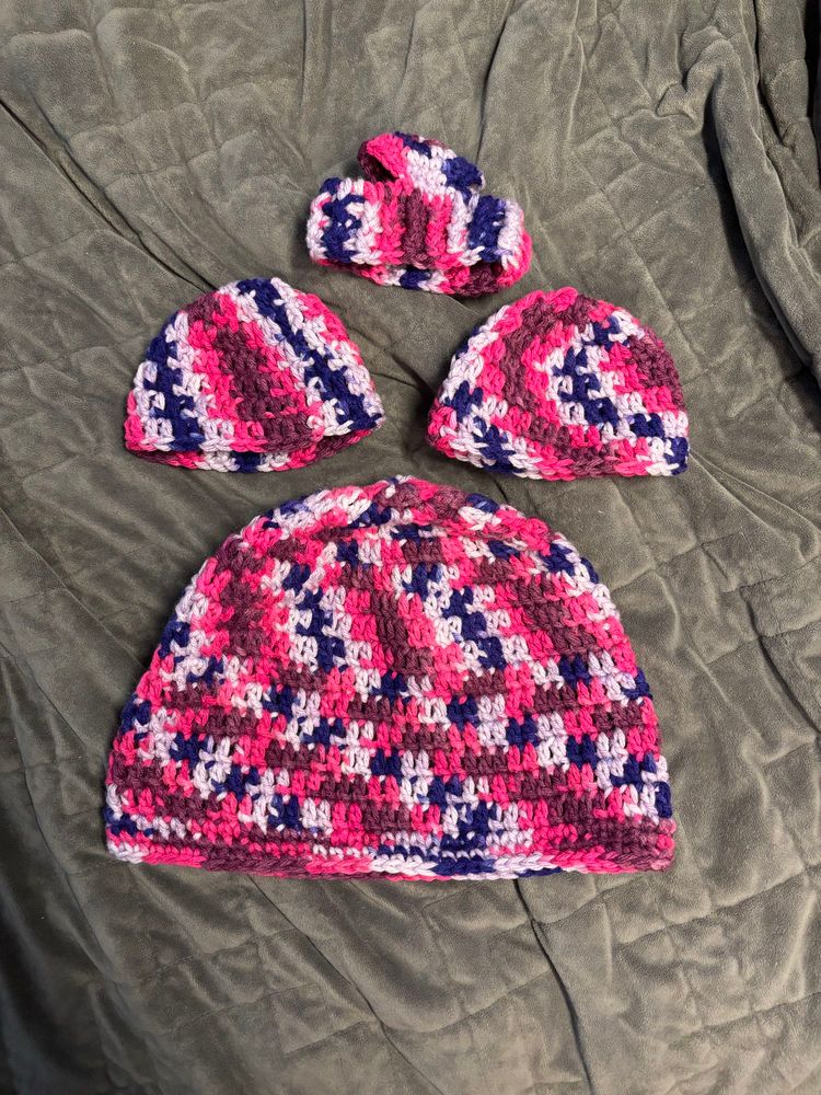 Four beanies are lying on a gray blanket.