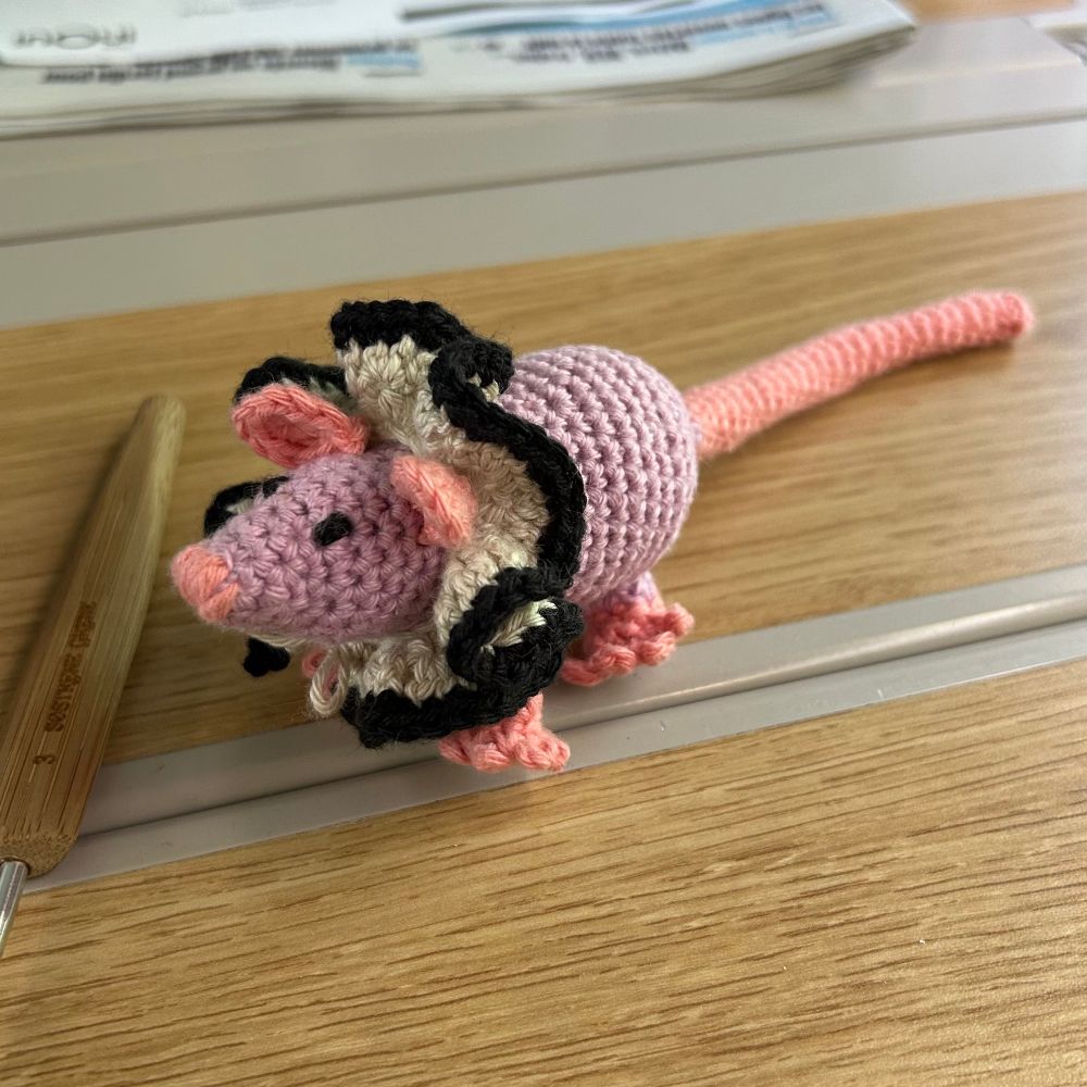 Photo du petit rat mignon que j'ai crocheté aujourd'hui : elle est mauve avec des membres roses. Elle porte une élégante collerette crème bordée de noir.