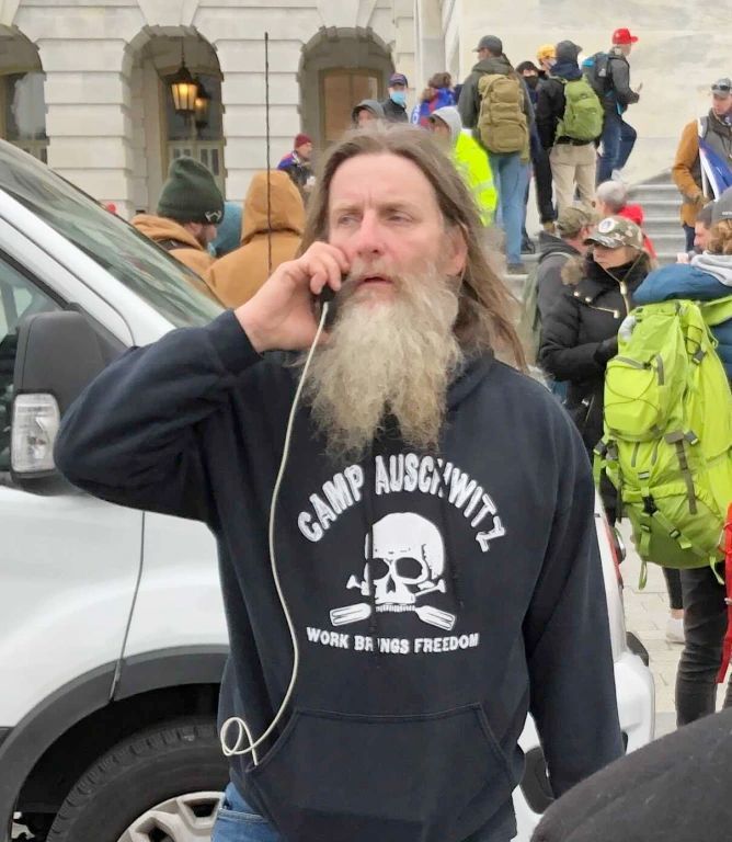 January 6 rioter wearing a hoodie featuring the words "Camp Auschwitz," a skull, and the phrase "Work Brings Freedom"
