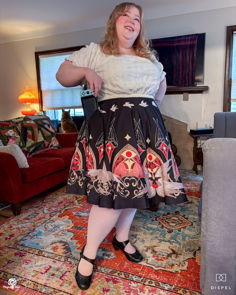 maya pulling a nintendo switch out of a black skirt with a biblically accurate angel design along the hem. she's wearing a size 2xl-3xl