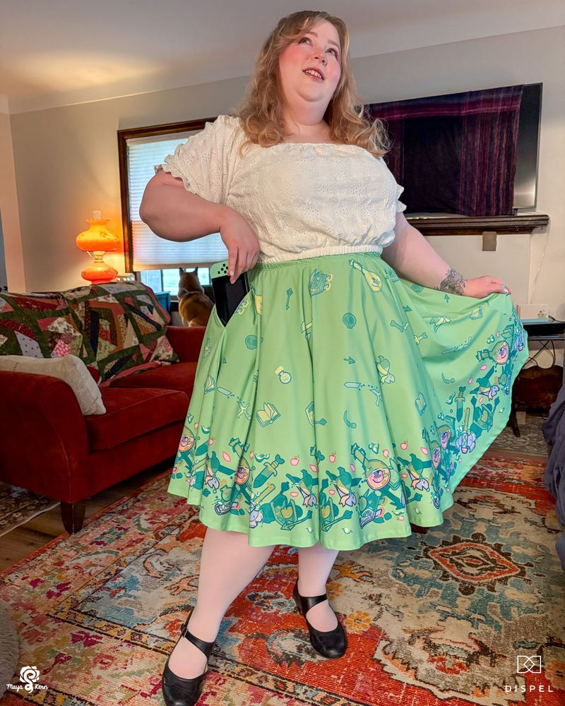 maya pulling a nintendo switch out of a green skirt with a gelatinous cube design. she's wearing a size 2xl-3xl