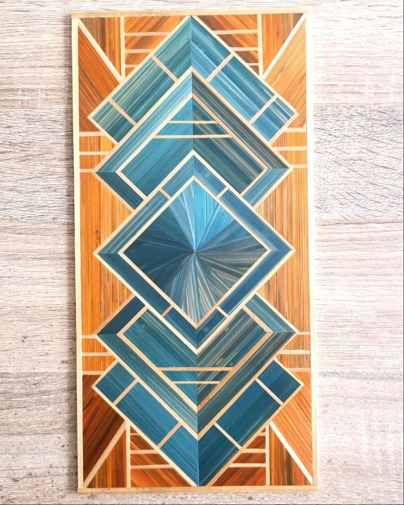 Tableau art deco en marqueterie de paille de 15*30cm. Le motif est un entralecement de 5 carré stylisé bleu vert sur fond cuivre. Les liseré sont en paille tabac. 