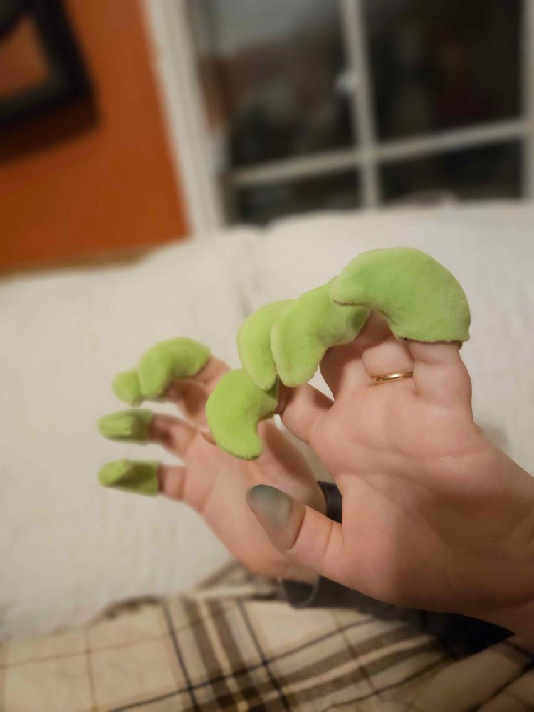 All eight green fursuit claws sewn up and finished, turned right side out and put on the tips of my fingers while my hands are posed in a "rawr" position. My thumbs(the only fingers without claws on them) are stained green from the water soluble marker I used when copying the pattern to the fabric.