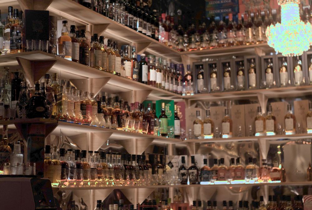 Bar shelf stocked with various bottles of liquor 