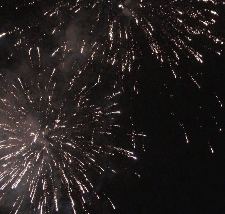 A grainy image of rose gold fireworks going off against a black sky.