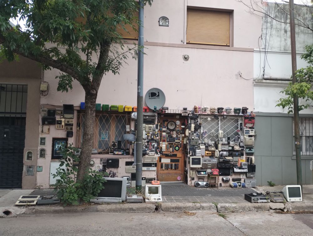 Frente de casa intervenido con tecnología vieja: teléfonos, televisores, máquinas de escribir, etc