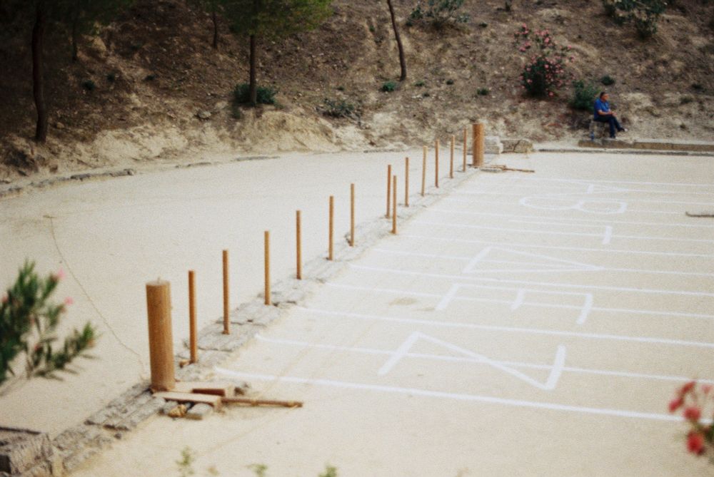 Picture of the ancient stadium of Nemea during the Modern Nemean Games in 2024. It shows the starting line with a reconstruction of an ancient starting mechanism, called Hysplex.