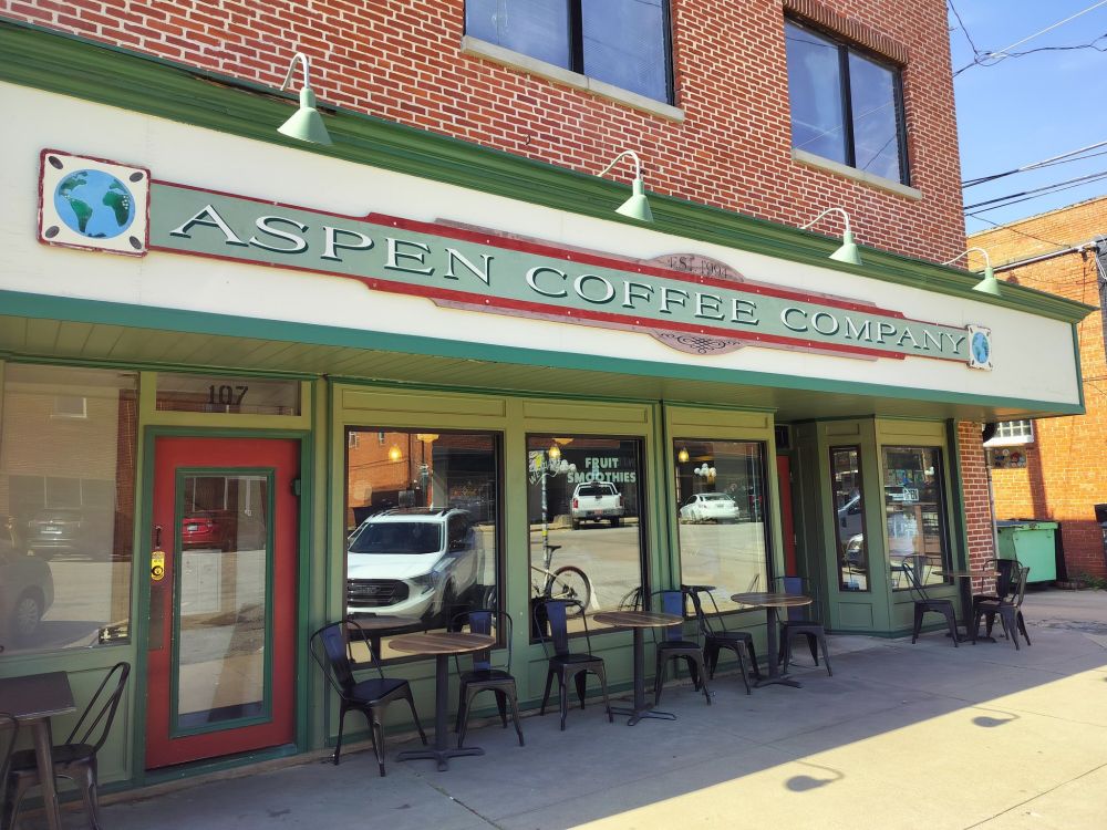 A coffee shop storefront with large windows and a red-and-green "Aspen Coffee Company" sign