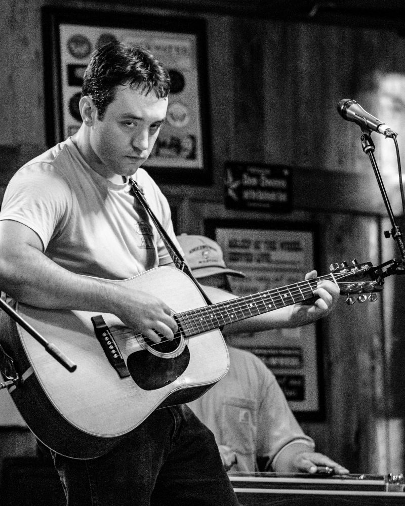 A black and white photo of a musician staring straight at the camera. 