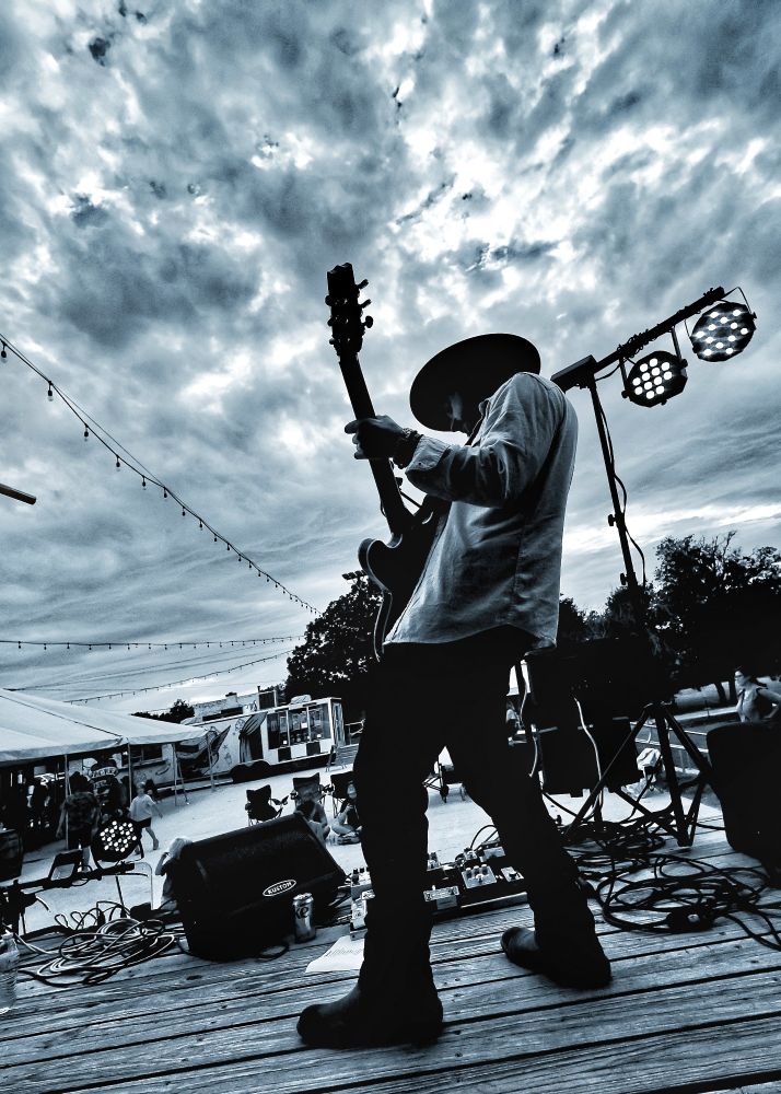 A guitarist takes a solo under a dramatic evening sky. 