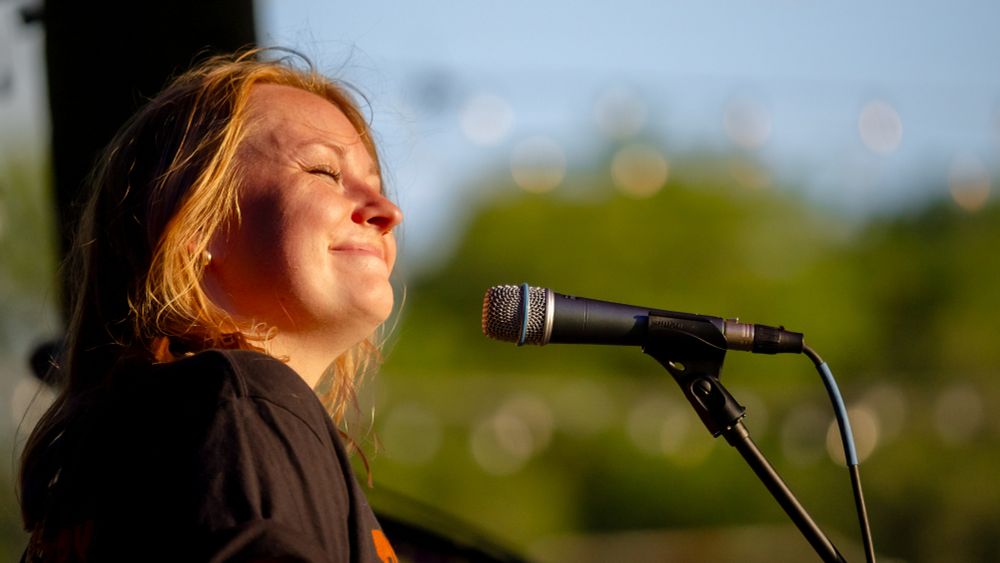 A singer squints and smiles during an outdoor concert. 