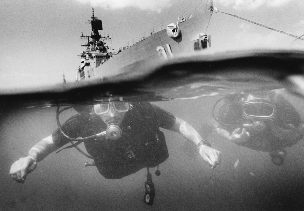 15-3001-0568 Navy divers in their natural environment. QMC (DV) Terry Miranda (left) and HT2(DV) Bob Bekesz tread the waters near the Seventh Fleet Guided Missile Cruiser USS Sterett (CG-31) in Subic Bay. [Divers][Ship] "Navy Dive Locker Gives Humanitarian Support" by PHI T. Salois, USN
