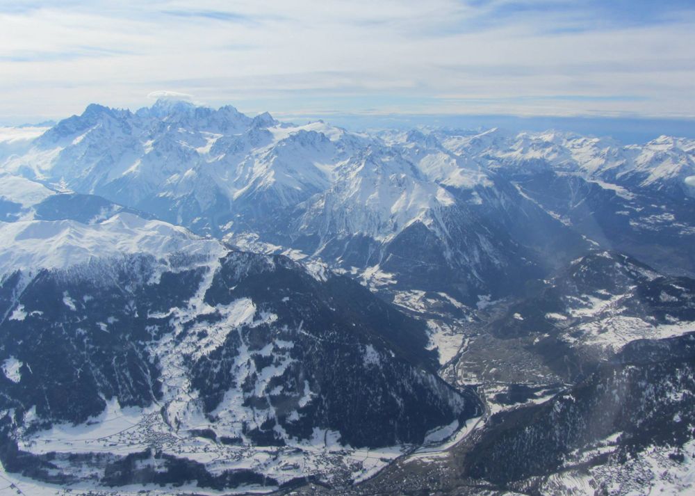 Picture taken from an airplane high above some snow covered mountains. 