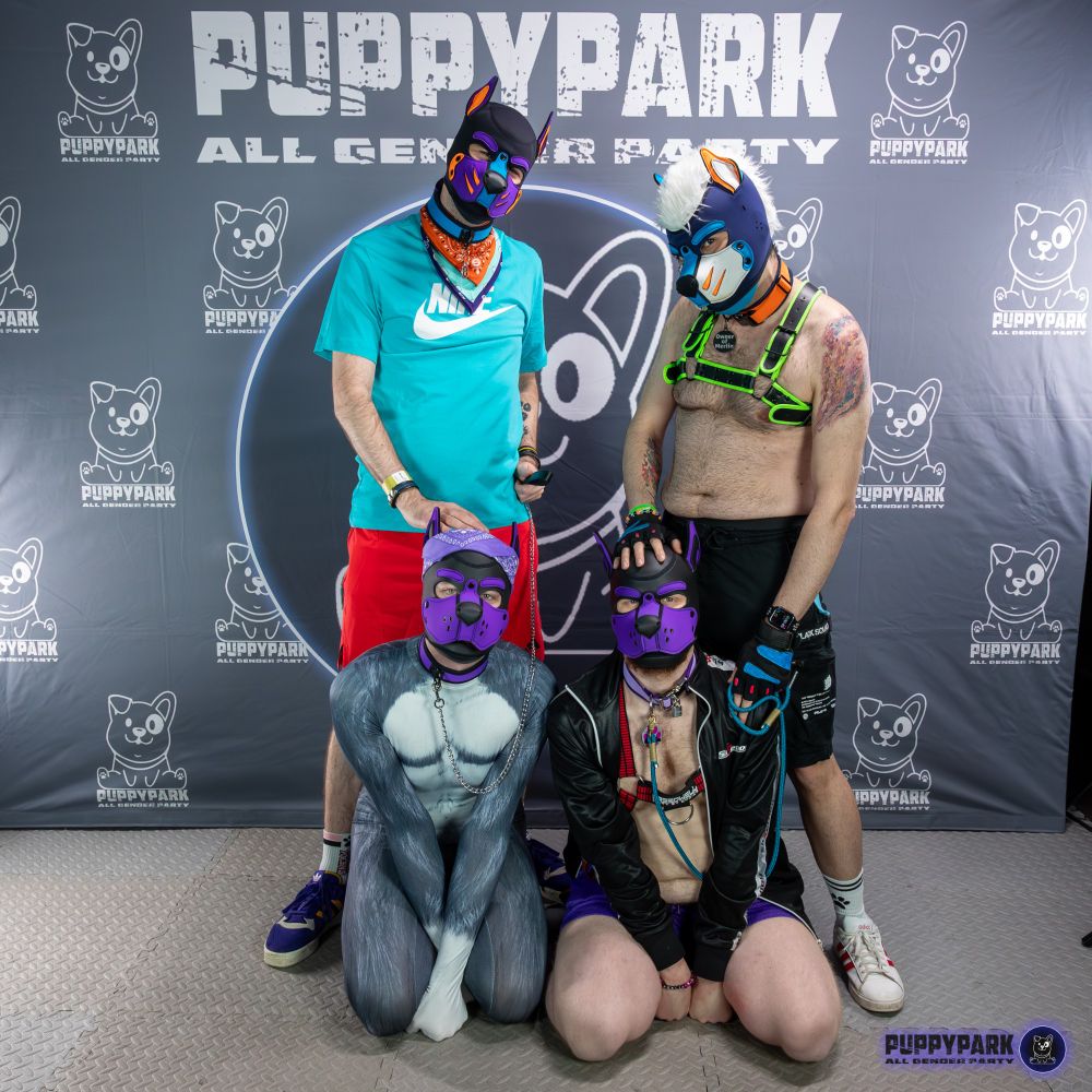 Kerbi und T1g3r stehen mit den sitzenden Akim und Merlin an der Leine vor der Fotowall.

Kerbi and T1g3r standing with the seating Akim and Merlin on a leash at the photo wall.