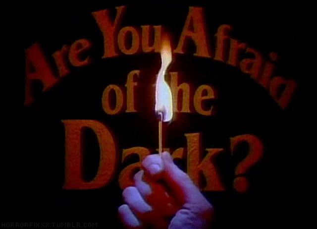 a person holding a lit match in front of a sign that says are you afraid of the dark