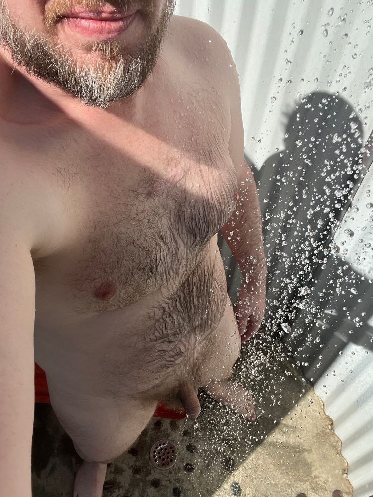 Man's naked body viewed from above in an outdoor shower.