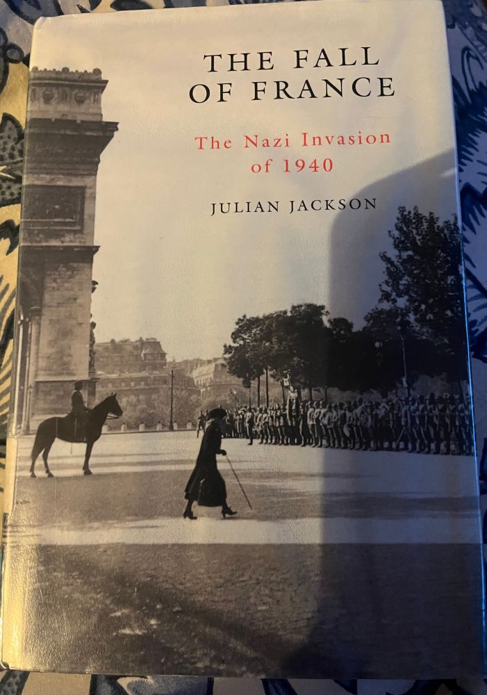 The cover of Julian Jackson’s book ‘The Fall Of France: The Nazi Invasion of 1940’. Cover photo is of a woman crossing ahead of Wehrmacht troops next to the Arc de Triomphe.