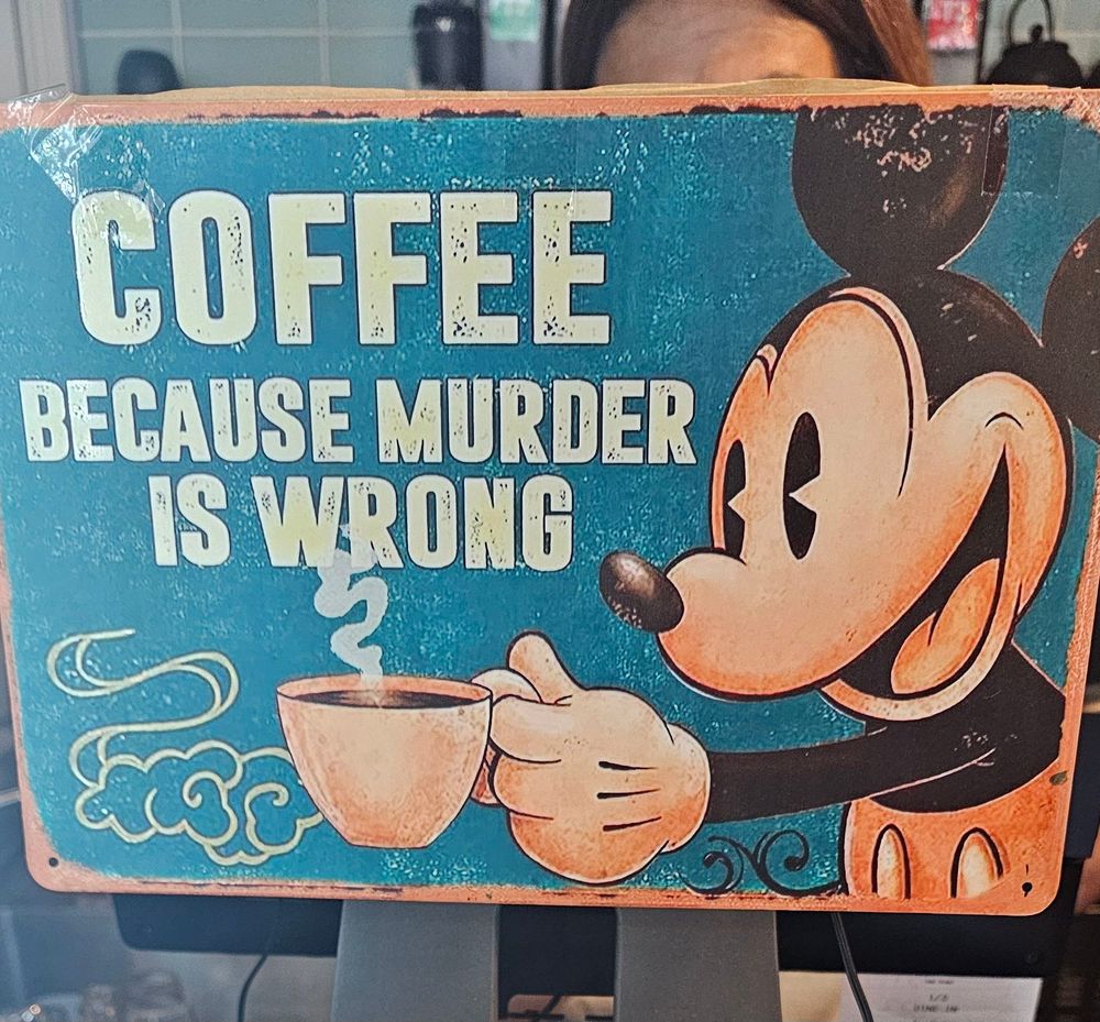 A metallic rustic-style sign that says "COFFEE
Because murder 
is WRONG" 
next to an off model picture of Mickey Mouse holding a cup of coffee somewhat towards the viewer, cup facing left.