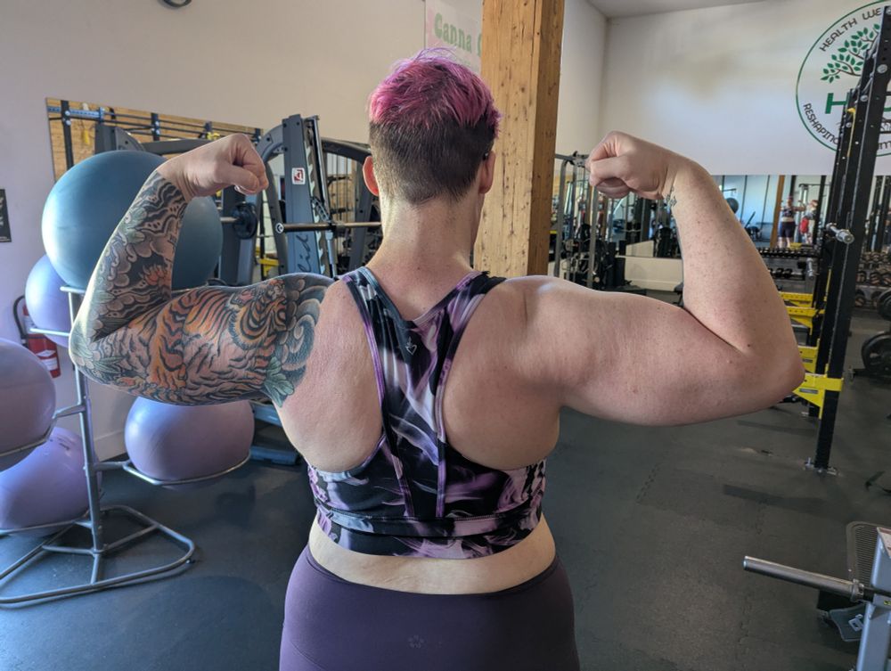 A womank flexing and showing her strong arms, back, and shoulders 